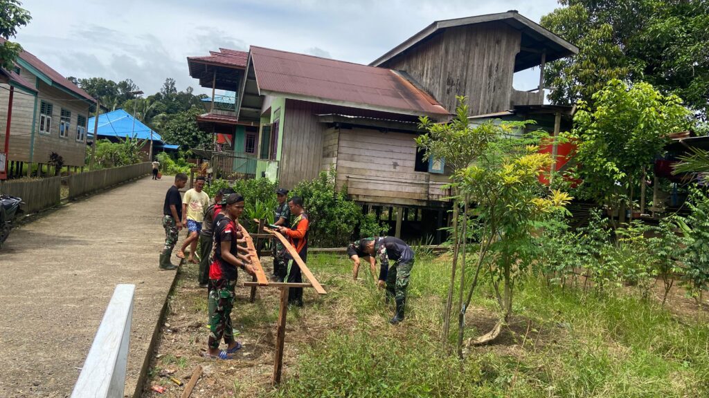 Anggota Satgas TMMD Membantu Membersihkan Pekarangan Rumah Warga