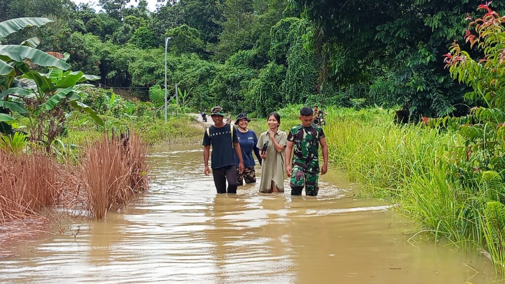 Bentuk Kepedulian, Anggota Satgas TMMD Bantu Warga Seberangi Banjir di Kampung Laham